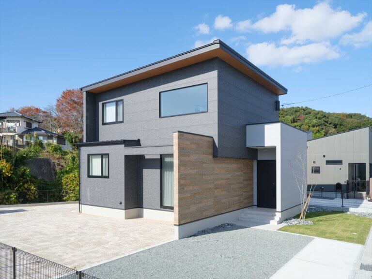 黒を基調に木目のアクセントが映え、落ち着きと温かみを感じる二階建ての外観です。